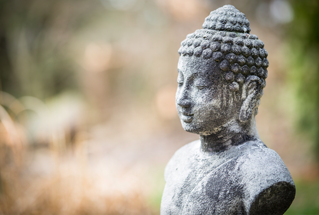 sculpture d'un bouddha en pierre serein dans la nature